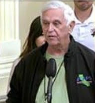 Don Antonowich speaking passionately at a public hearing with a microphone.