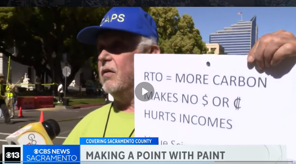 CAPS-UAW members rallying outdoors for fair pay, holding a sign at a May Day event.